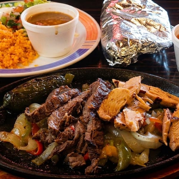 Sizzling fajitas with steak, chicken, peppers, and onions, served with rice, beans, and salsa.
